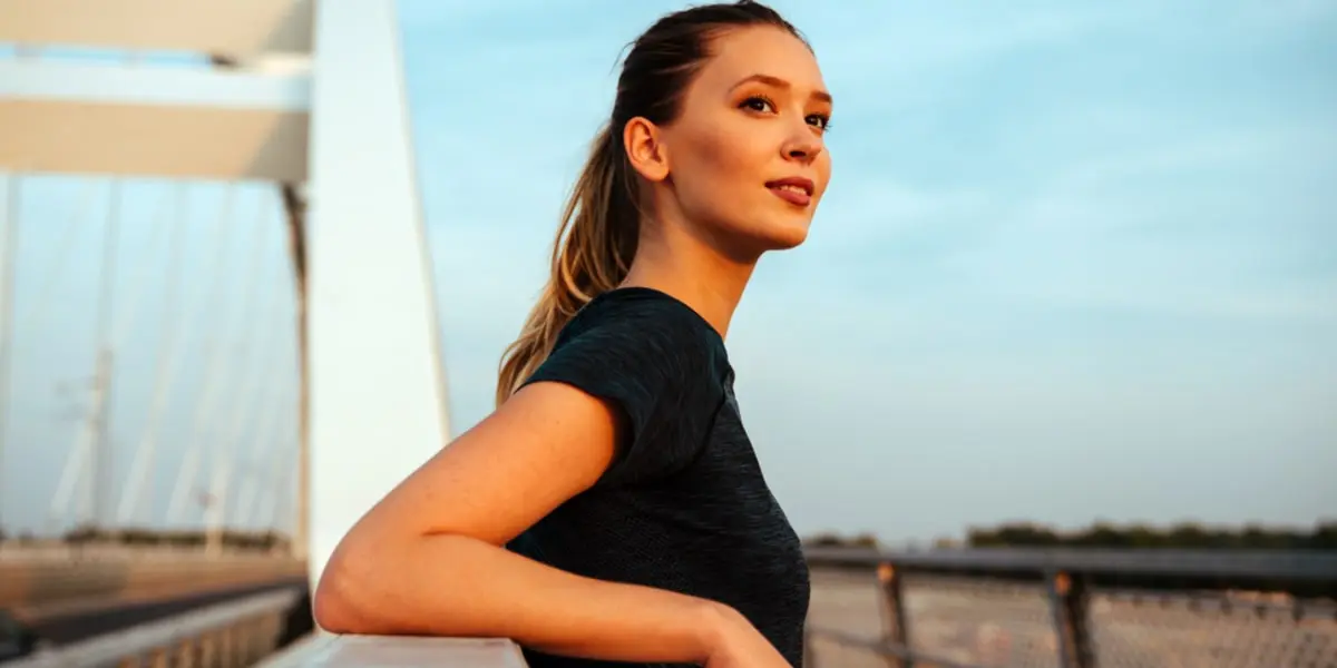 Jeune fille regardant l'horizon appuyée sur la rambarde d'un pont Jeune fille regardant l'horizon appuyée sur la rambarde d'un pont